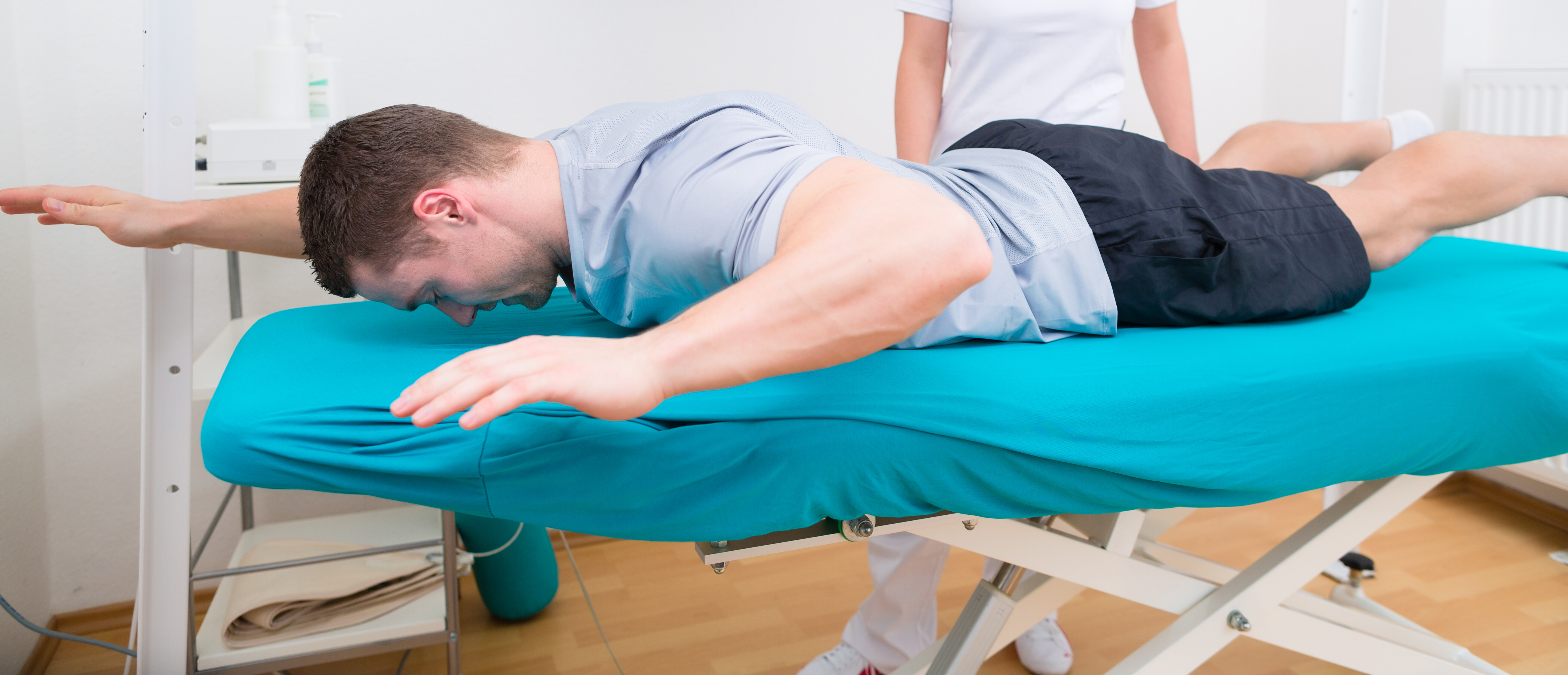 Man lying face down on a treatment table doing physical therapy exercises